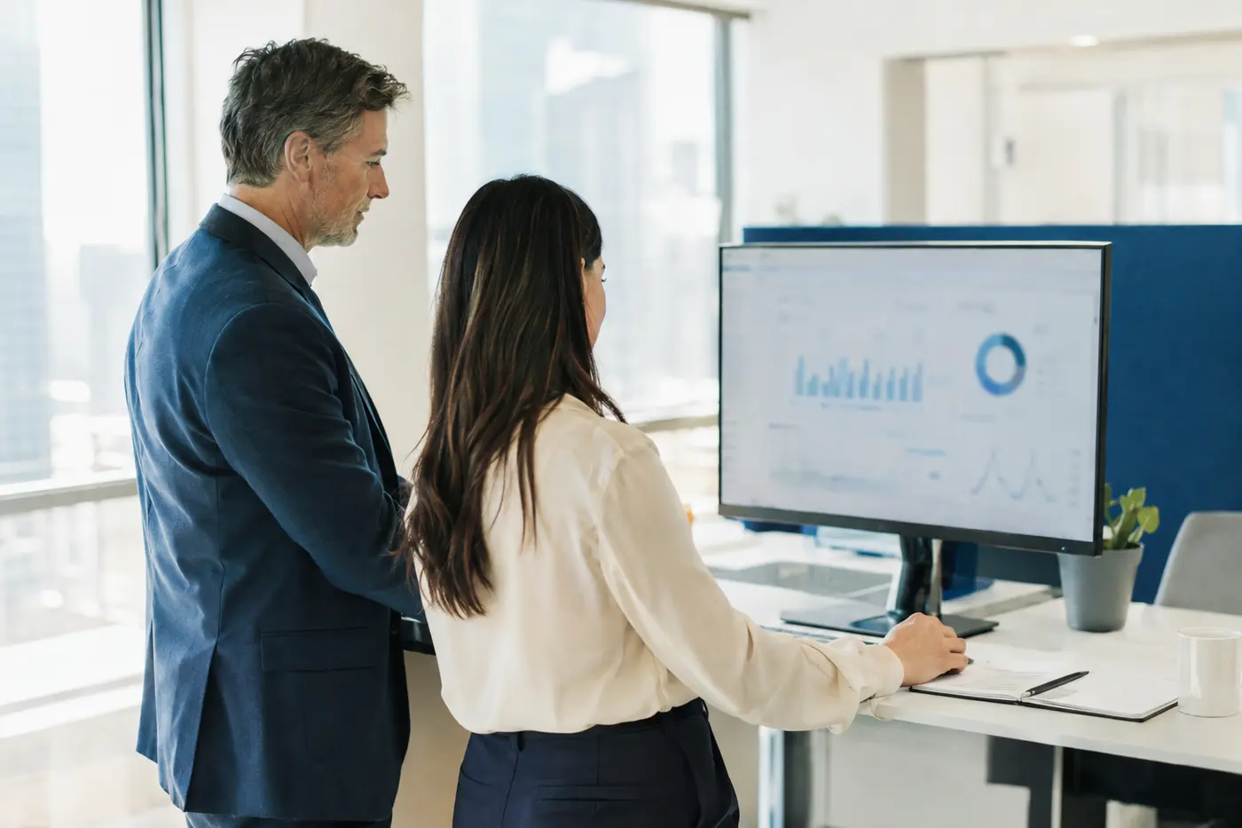 Two colleagues reviewing a call performance dashboard on a large monitor